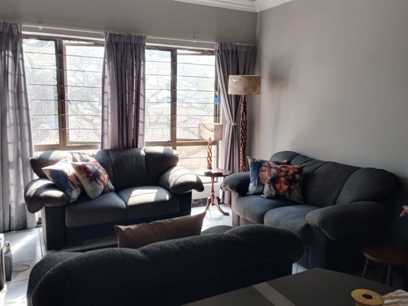 A comfortable living room featuring large windows that provide ample natural light and tiled flooring throughout.