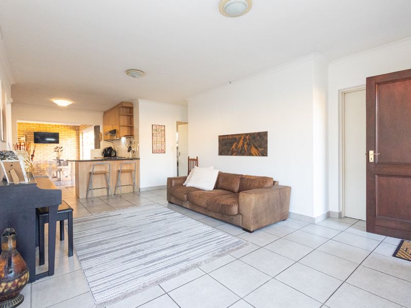 Open plan living area featuring tiled flooring, a functional kitchen with breakfast bar, and direct access to the main entrance.