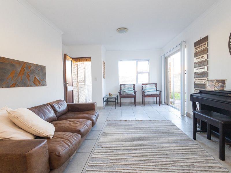 A bright living room featuring tiled flooring, neutral walls, and a sliding glass door providing access to the outdoor area.