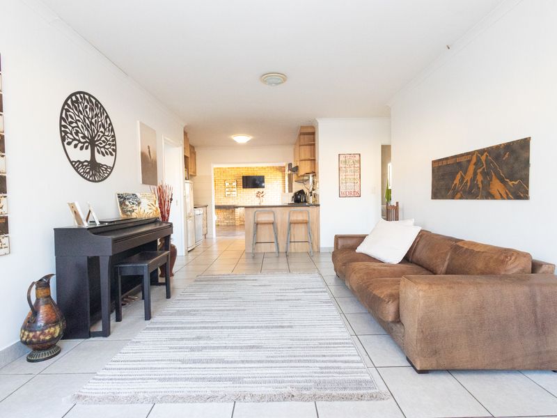 Open plan living area featuring tiled flooring and a functional kitchen with a breakfast bar, creating a versatile space for daily living.