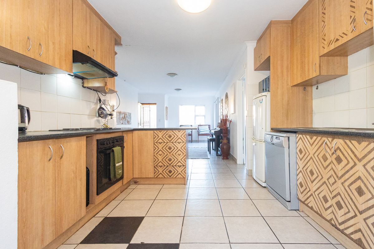 A functional kitchen featuring laminate cabinetry, built-in oven, extractor fan, and tiled flooring, offering a practical layout with potential for modern updates.