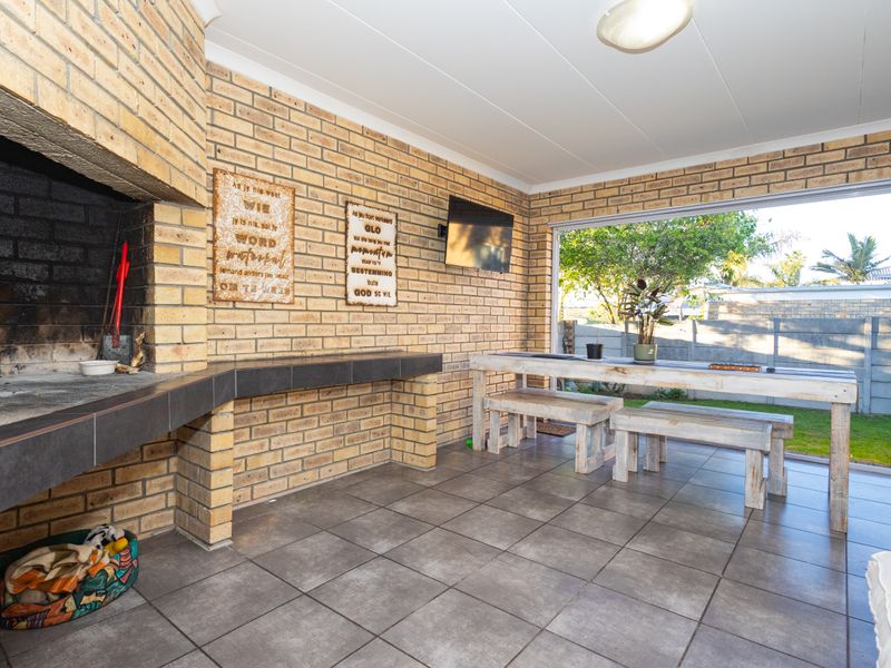Covered patio area featuring a built-in brick braai, tiled flooring, and direct access to the garden.