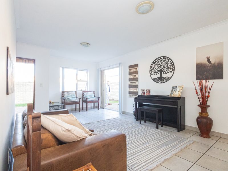 A bright living room featuring tiled flooring, neutral walls, and a sliding glass door providing direct access to the outdoor area.