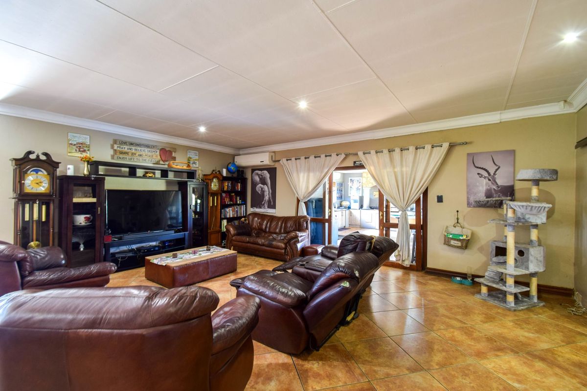 Spacious living room featuring tiled flooring, recessed lighting, and direct access to the kitchen area through double doors.