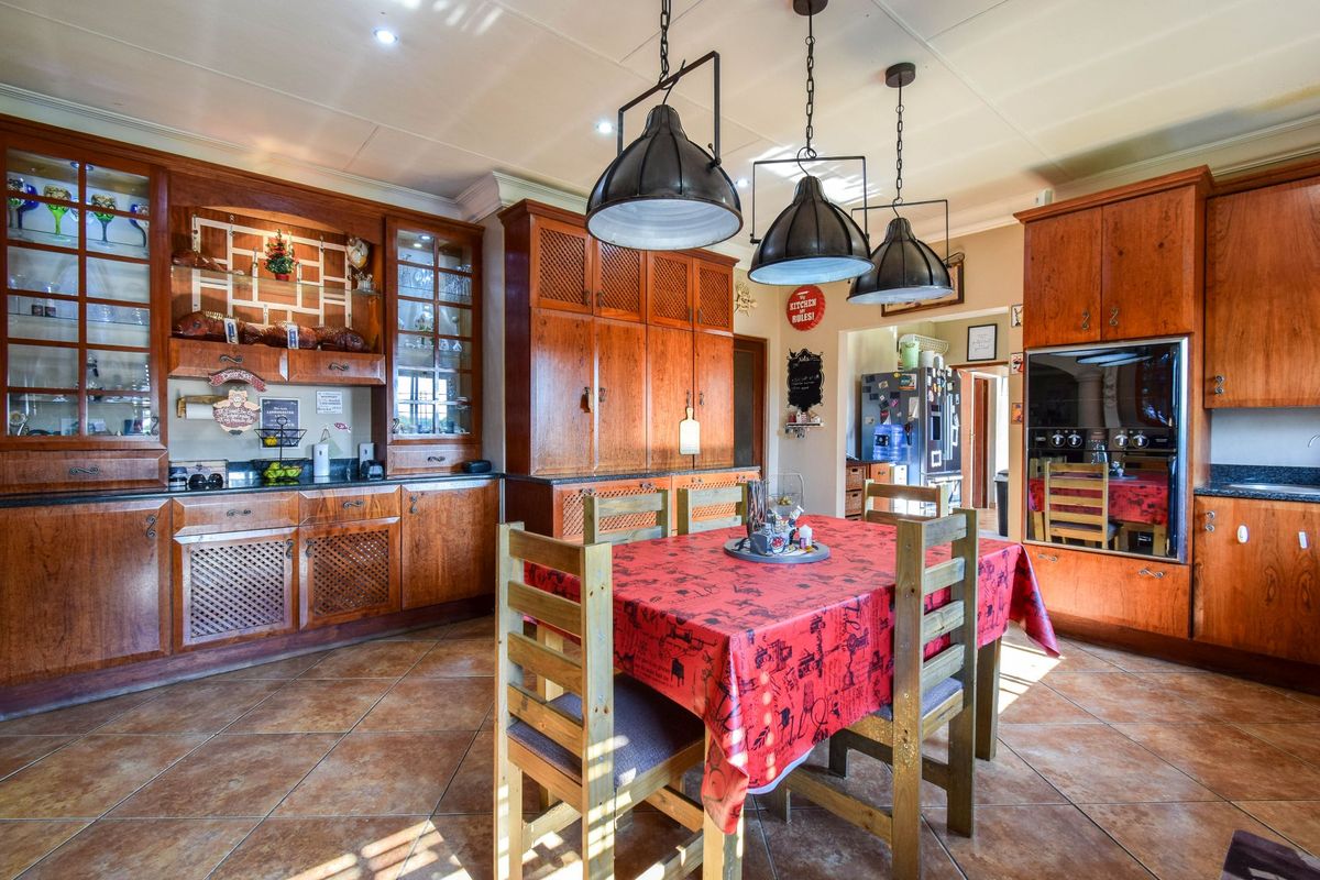 Spacious kitchen featuring extensive wooden cabinetry, integrated oven, and tiled flooring, offering a warm and traditional aesthetic with ample storage space.