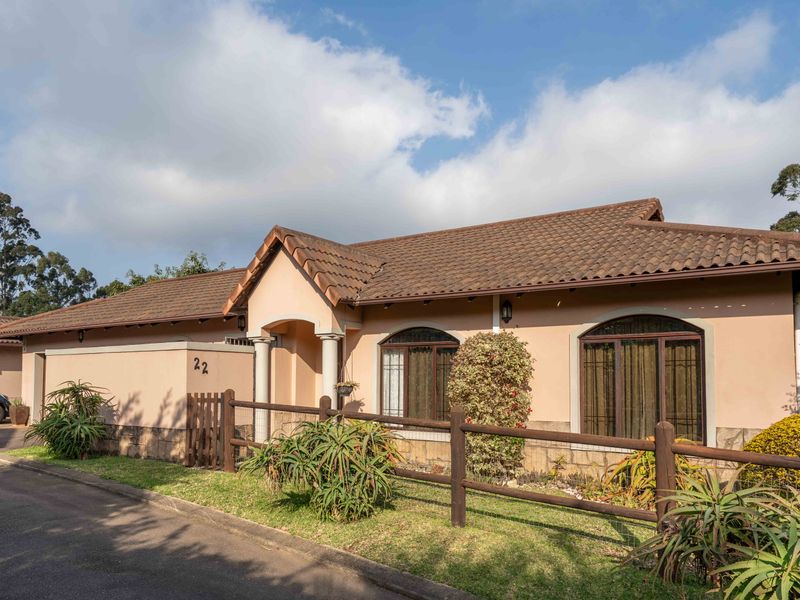 Front elevation of a townhouse featuring a tiled roof, arched windows, stone cladding accents, and a covered entrance with pillars.
