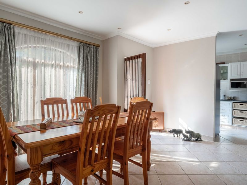 Open-plan dining area featuring tiled floors and recessed lighting, with a view into the adjacent kitchen space.