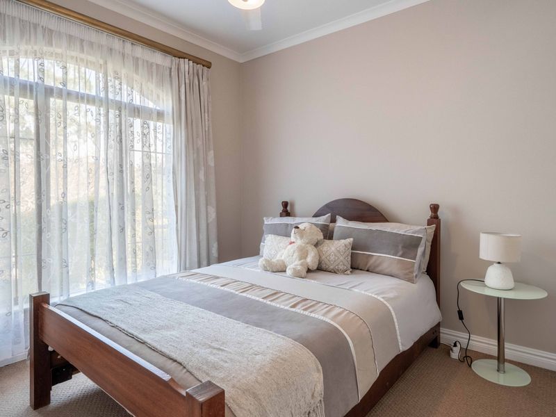 A well-maintained bedroom featuring neutral wall tones, carpeted flooring, and a large arched window that allows for ample natural light.
