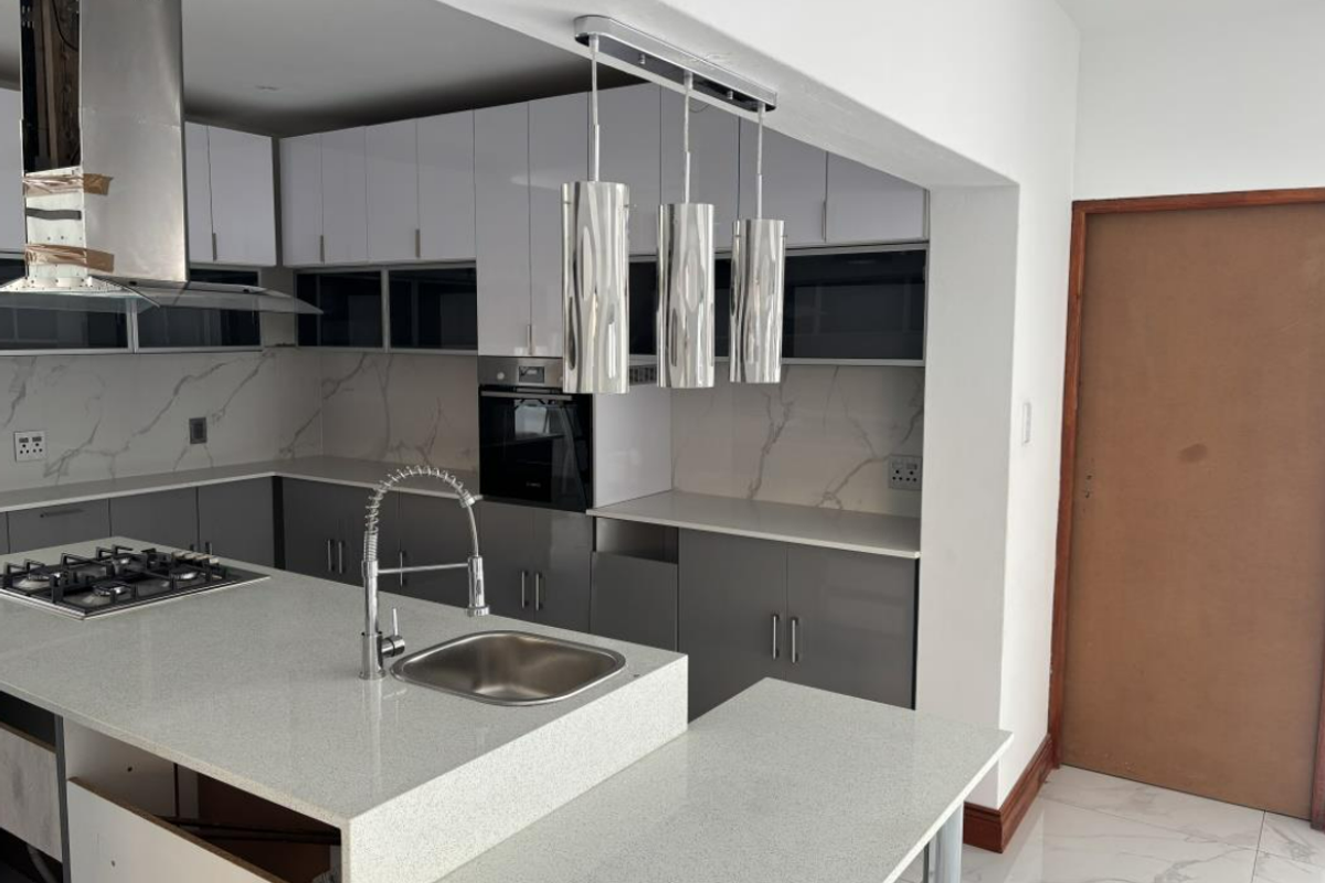 Modern kitchen featuring gloss cabinetry, quartz countertops, gas hob, built-in oven, and marble-look splashback, currently in an unfinished state.