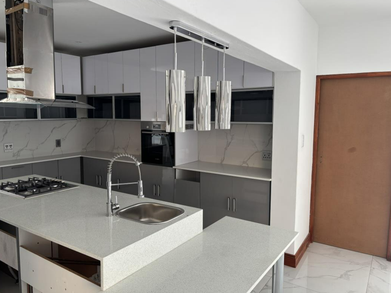 Modern kitchen featuring gloss cabinetry, quartz countertops, gas hob, built-in oven, and marble-look splashback, currently in an unfinished state.