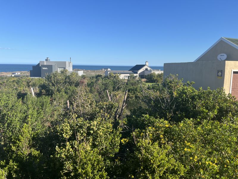 A scenic view overlooking the coastal landscape and surrounding residential properties, showcasing the natural vegetation and ocean horizon.