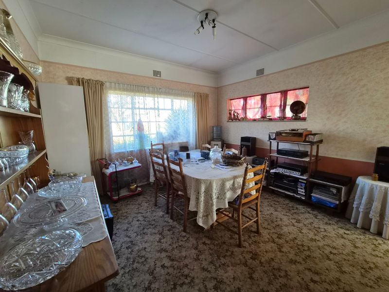 A dated dining room featuring large windows, built-in shelving, and original carpeting, offering a spacious layout ready for modern updates.