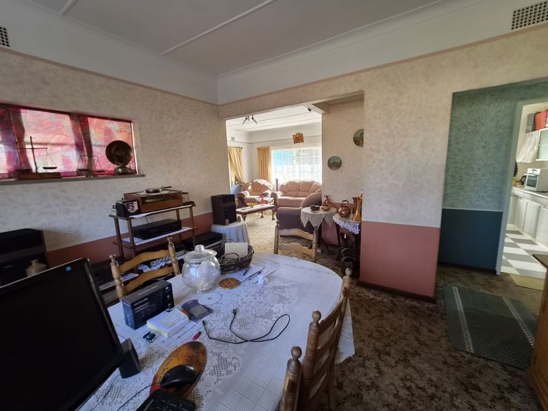 Open plan living and dining area featuring dated finishes, carpeted flooring, and a view through to the adjacent kitchen space.