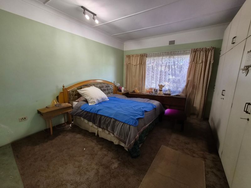 A bedroom featuring built-in cupboards, carpet flooring, and ceiling track lighting, offering a functional space ready for cosmetic updates.