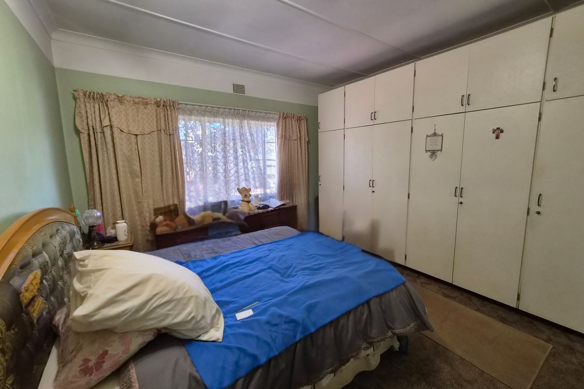 A bedroom featuring extensive built-in floor-to-ceiling cupboards and a window with natural light.