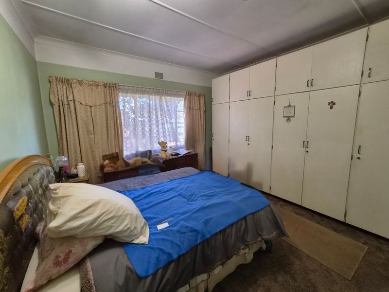 A bedroom featuring extensive built-in floor-to-ceiling cupboards and a window with natural light.