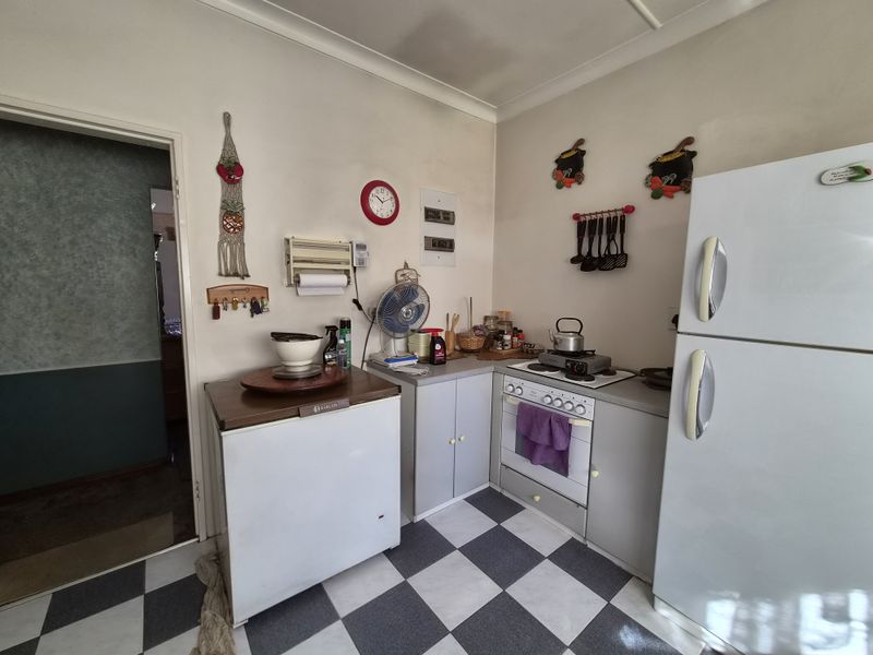 A compact kitchen featuring built-in cabinetry, a stove with oven, and checkered flooring, offering a functional layout with potential for modern updates.