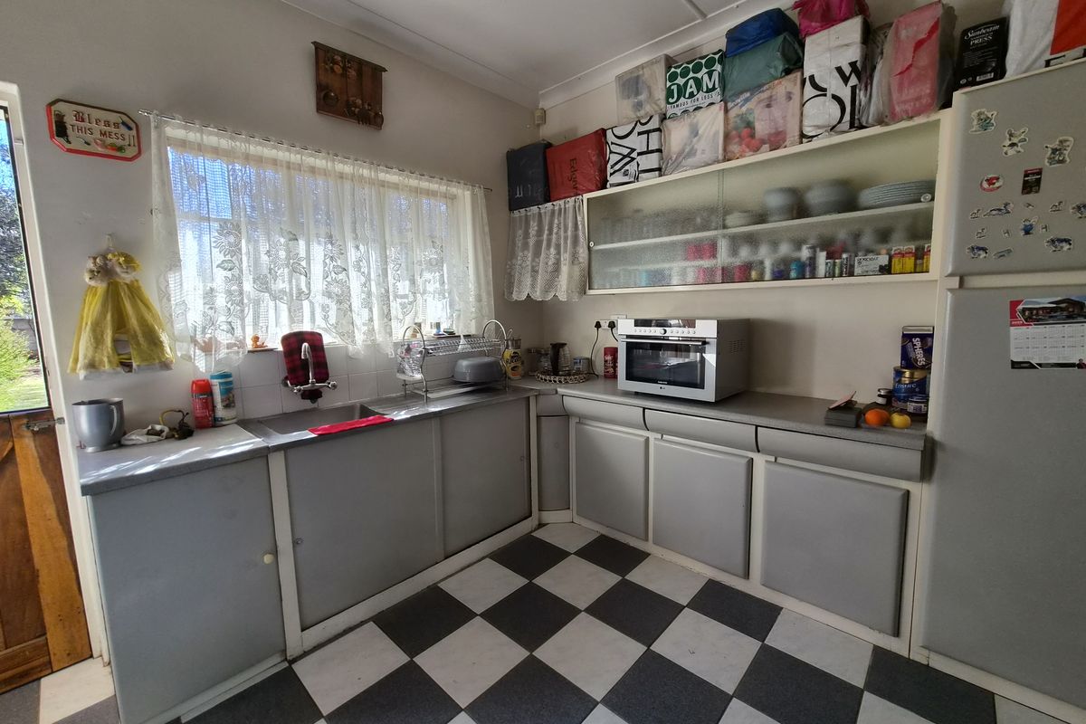 A functional kitchen featuring laminate countertops, a stainless steel sink, and classic checkered flooring, offering potential for a modern renovation.