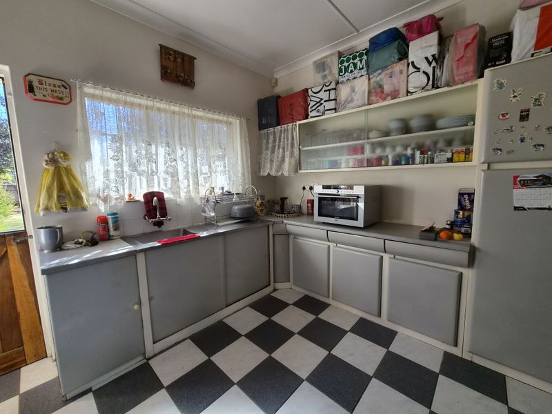 A functional kitchen featuring laminate countertops, a stainless steel sink, and classic checkered flooring, offering potential for a modern renovation.