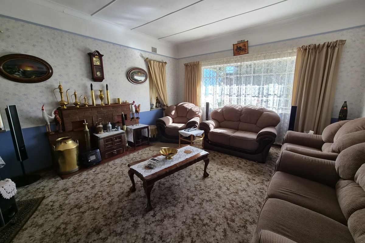 A traditional living room featuring a brick fireplace, large window, and coved ceilings, offering a classic layout ready for modern updates.