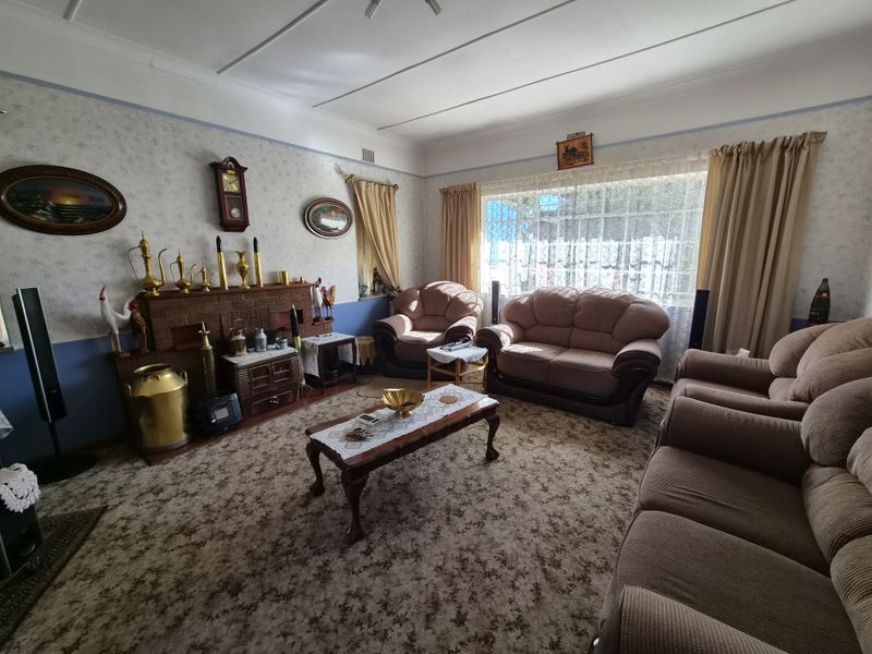 A traditional living room featuring a brick fireplace, large window, and coved ceilings, offering a classic layout ready for modern updates.