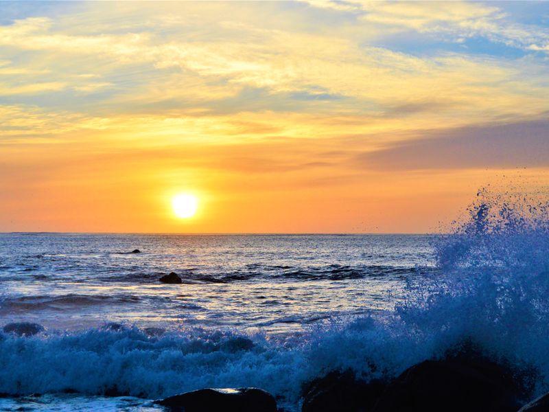A scenic view of the ocean at sunset with crashing waves, highlighting the natural landscape and coastal setting of the property.