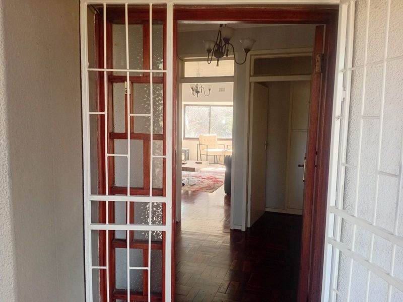 Entrance area featuring a security gate, wooden door frame, and classic parquet flooring leading into the main living space.