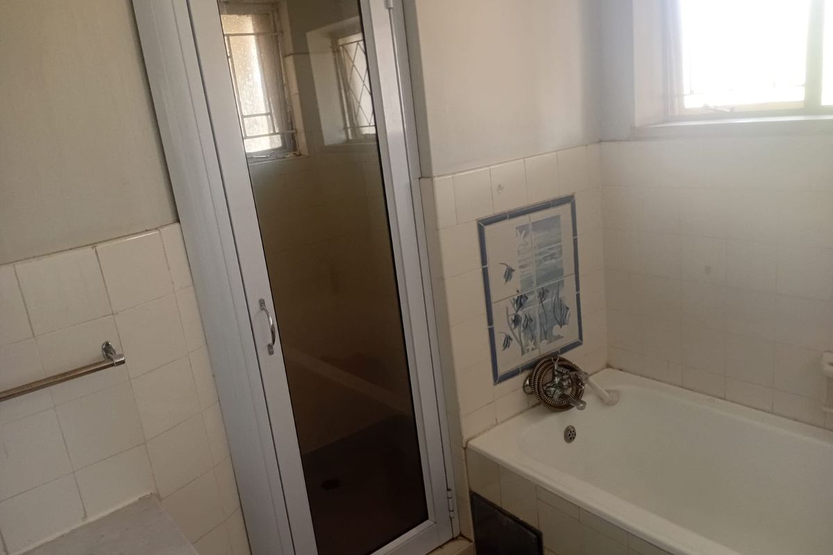 A dated bathroom featuring a bathtub, separate shower enclosure, and tiled walls, offering potential for a modern renovation.