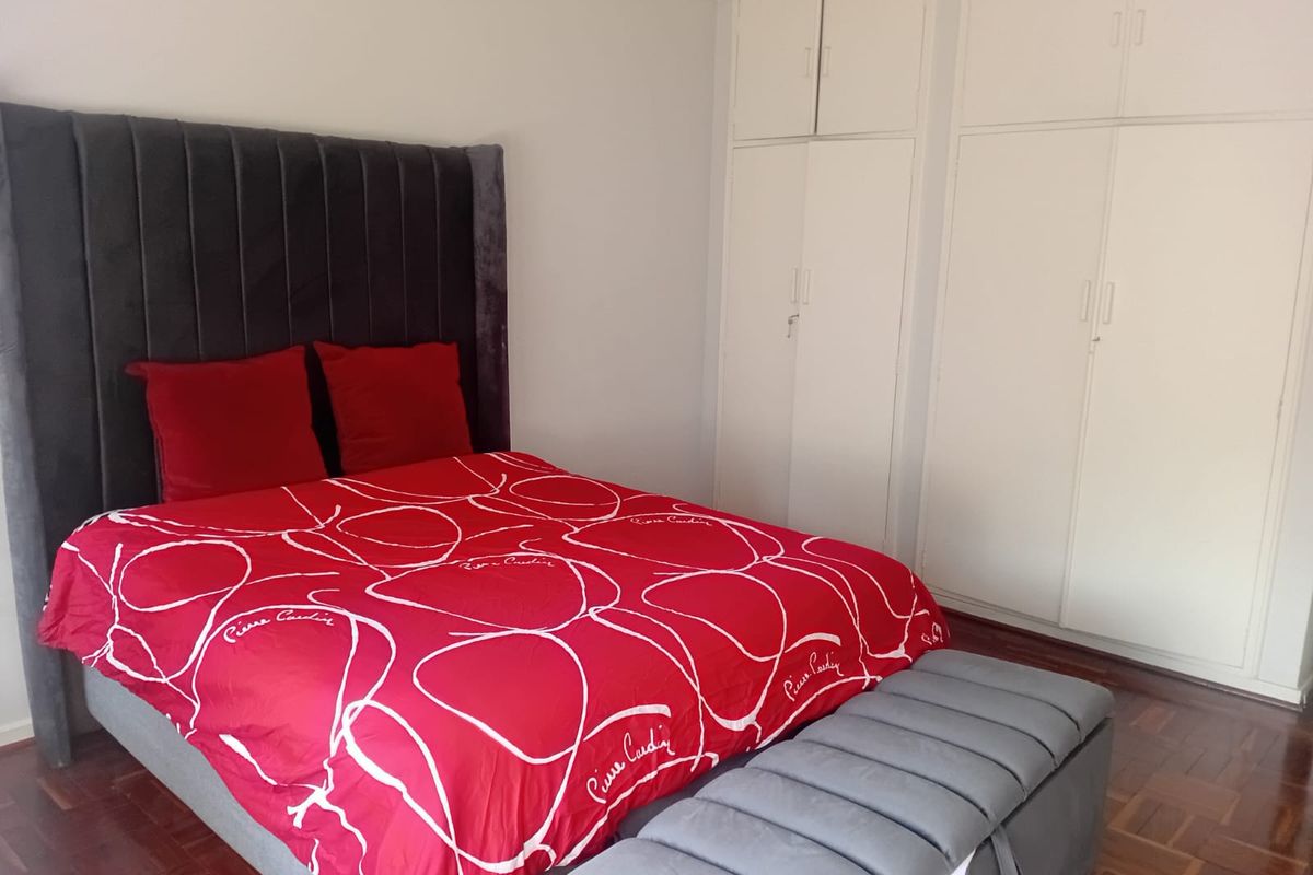 A well-maintained bedroom featuring classic parquet flooring and ample built-in cupboard storage space.