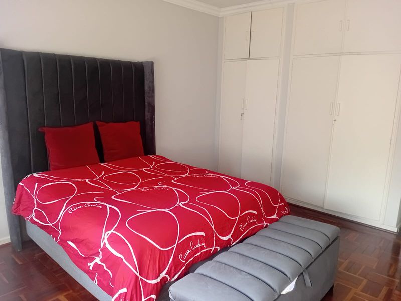 A well-maintained bedroom featuring classic parquet flooring and ample built-in cupboard storage space.
