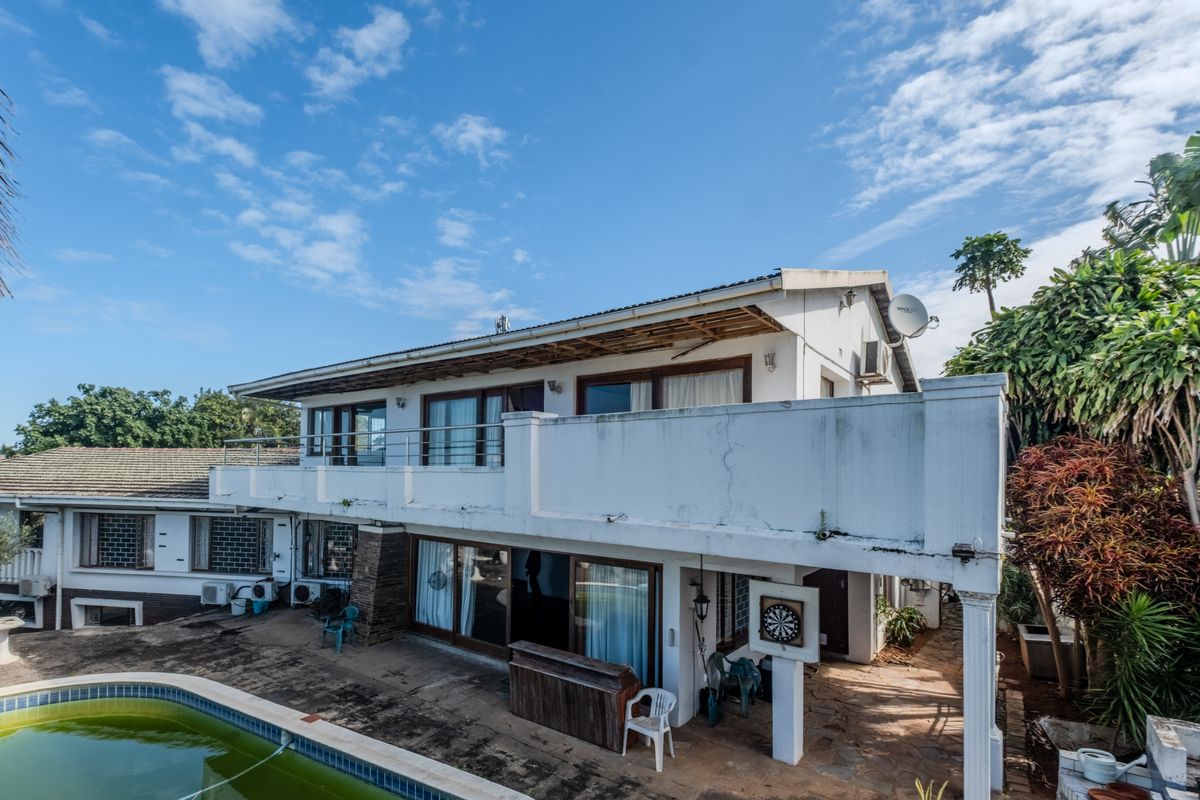 Rear view of a multi-level house featuring a balcony, sliding glass doors, and an outdoor swimming pool area requiring maintenance.