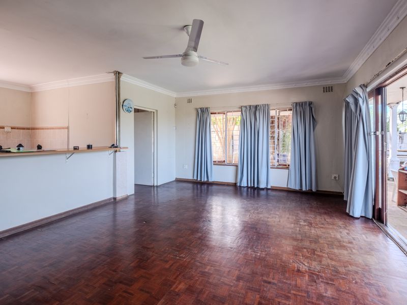 Spacious open-plan living area featuring parquet flooring, a ceiling fan, and direct access to an outdoor patio through sliding glass doors.