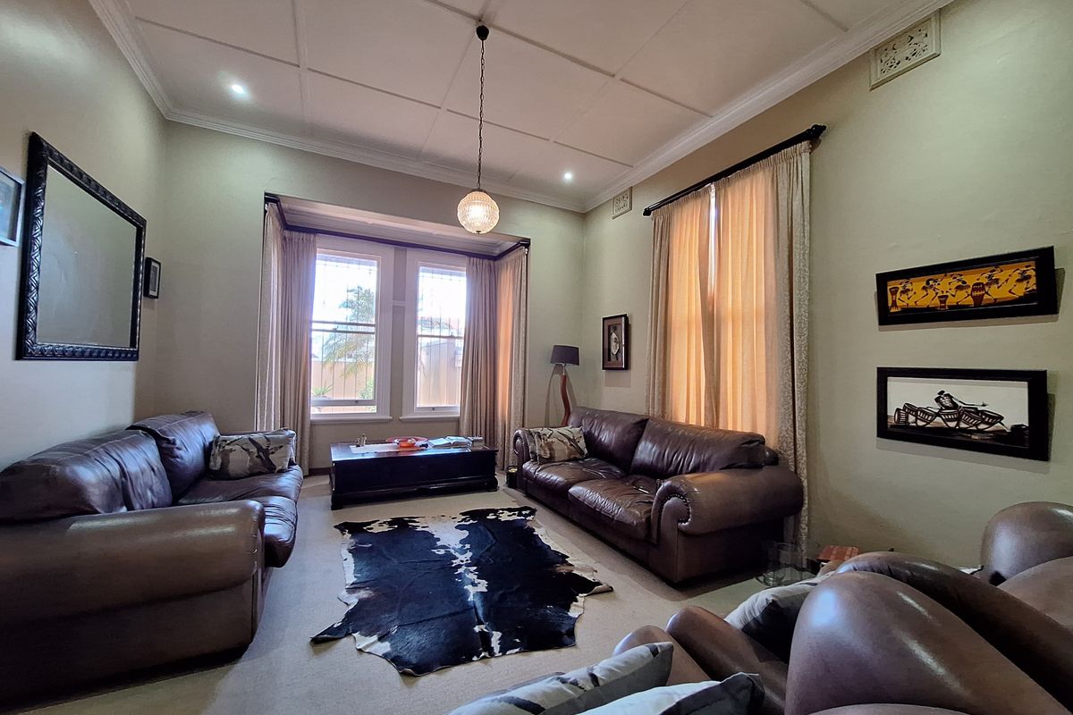 A spacious living room featuring a classic coffered ceiling, large sash windows, and neutral wall finishes, offering a comfortable and traditional living space.