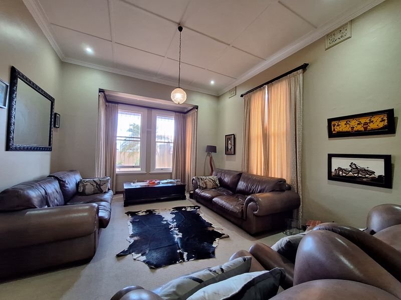 A spacious living room featuring a classic coffered ceiling, large sash windows, and neutral wall finishes, offering a comfortable and traditional living space.