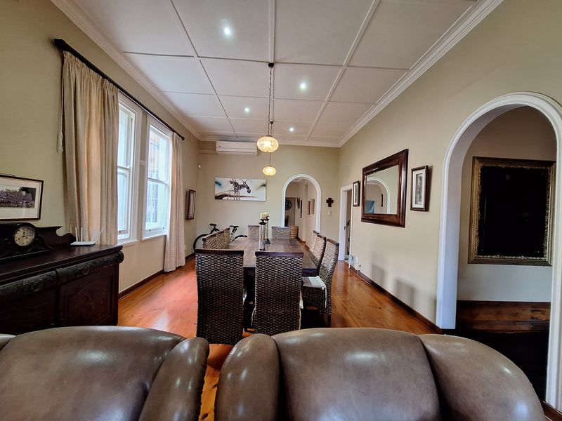 Spacious dining room featuring polished hardwood flooring, a classic coffered ceiling with recessed lighting, and elegant arched doorways leading to adjacent living areas.