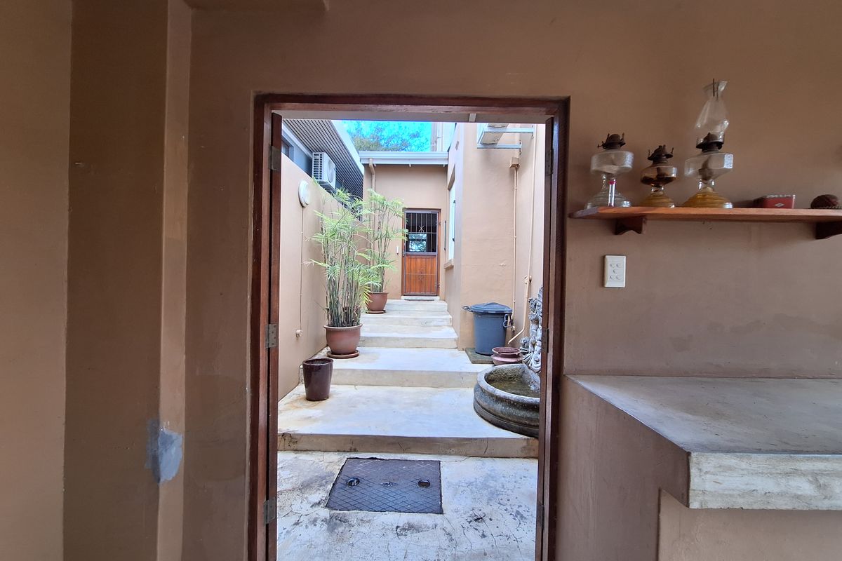 A rear courtyard area featuring concrete steps, a stone water feature, and a built-in counter, providing a rustic outdoor space with potential for enhancement.