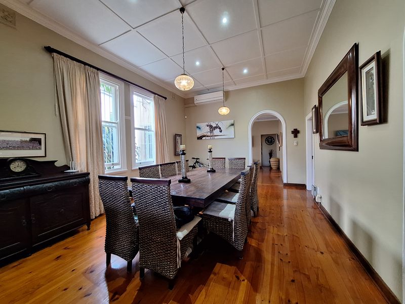Spacious dining room featuring polished timber flooring, a decorative coffered ceiling, and an elegant archway leading to the hallway.