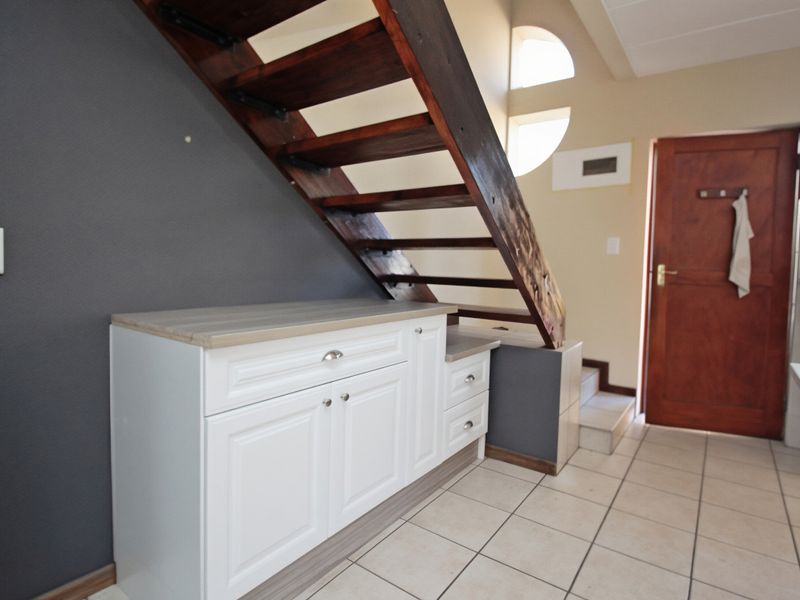 Entrance area featuring a wooden staircase, built-in storage cabinetry, tiled flooring, and a solid wood door with natural light from a circular window.