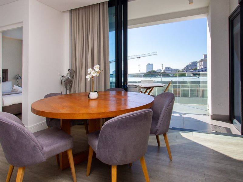 Bright open-plan living area featuring modern tiled flooring and large sliding glass doors that open onto a private balcony with urban views.