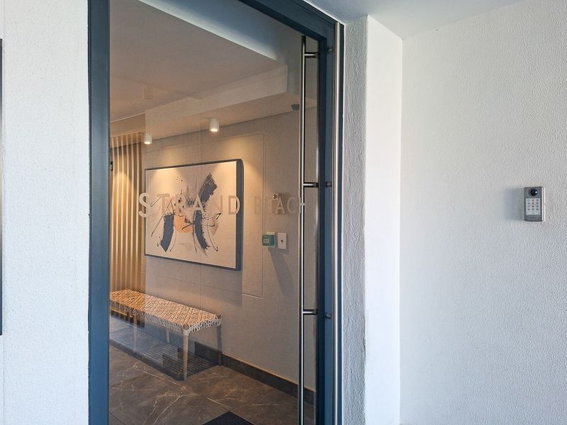 Modern apartment building entrance featuring a secure glass door, intercom access system, and clean, contemporary finishes in the lobby area.