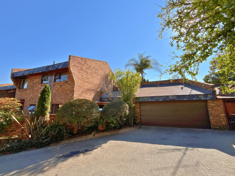 Front exterior view of a townhouse featuring a face brick facade, slate roof tiles, and a double garage with a paved driveway.
