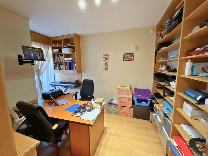 A functional home office featuring built-in wooden shelving units and laminate flooring, providing a dedicated workspace within the townhouse.