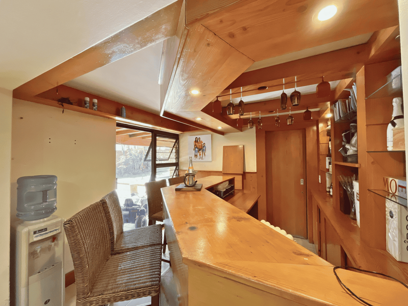 A dedicated home bar area featuring custom timber cabinetry, a built-in bar counter, and integrated shelving with recessed lighting.