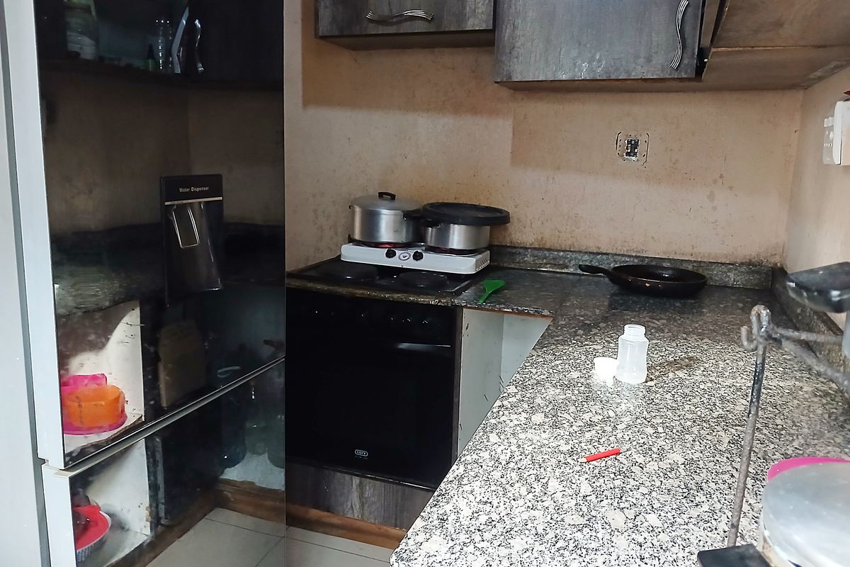 A compact kitchen featuring granite countertops, built-in cabinetry, and an integrated oven, currently showing signs of wear and requiring cosmetic updates.