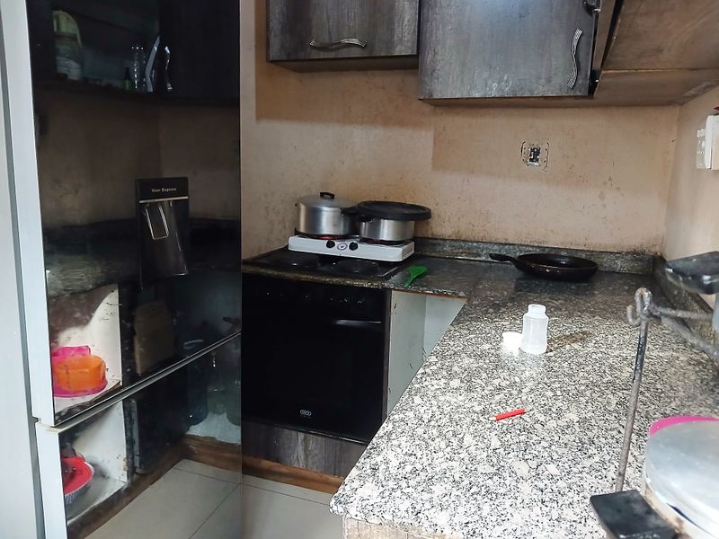 A compact kitchen featuring granite countertops, built-in cabinetry, and an integrated oven, currently showing signs of wear and requiring cosmetic updates.