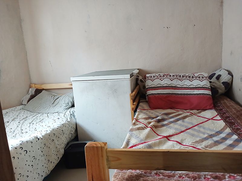 A bedroom space featuring plain walls in need of maintenance and repainting.