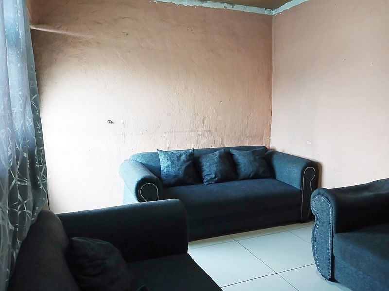 A living room area featuring tiled flooring and plain walls requiring cosmetic attention and finishing touches.