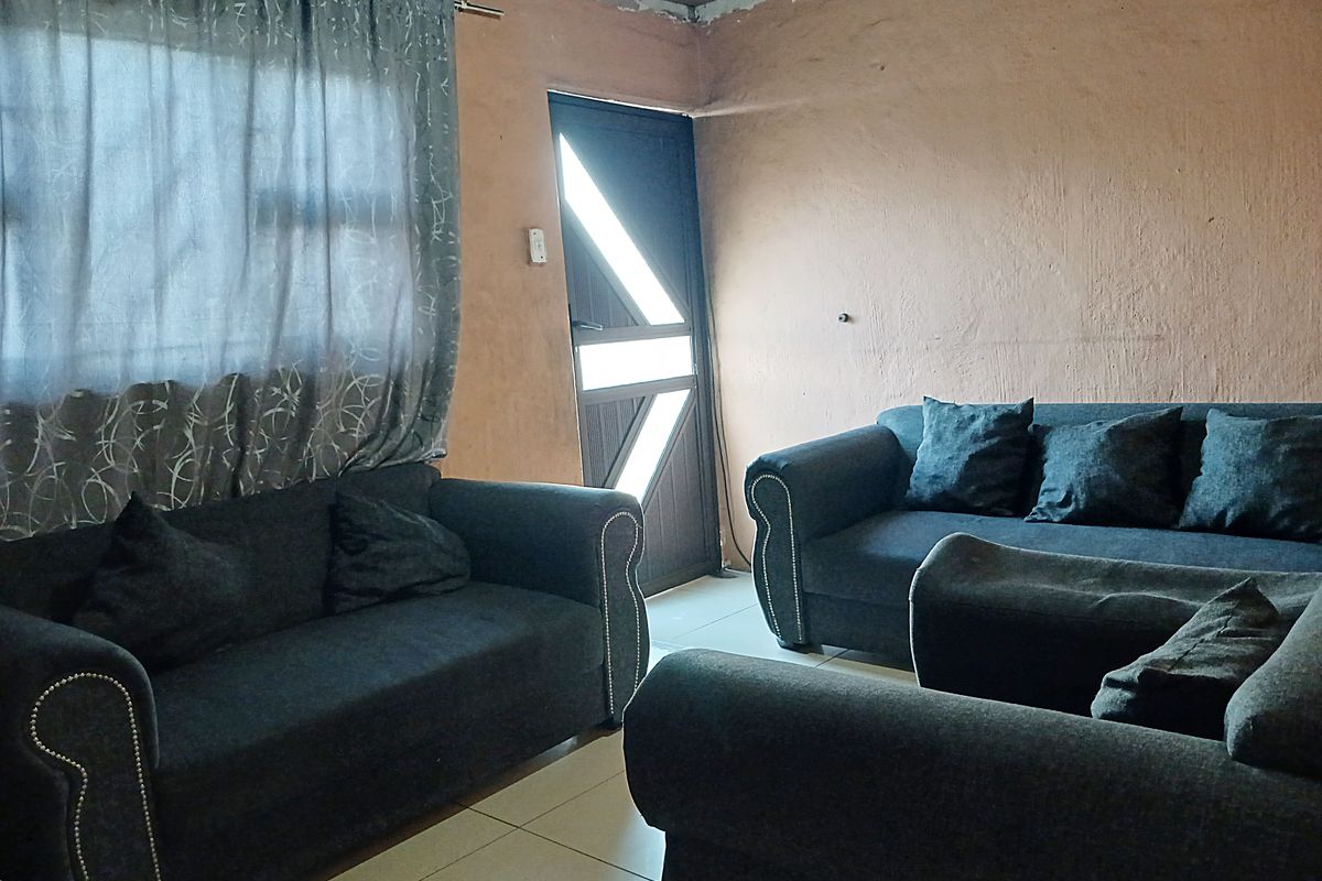 A living room area featuring tiled flooring and an external door, currently requiring cosmetic updates to the wall finishes and ceiling junctions.