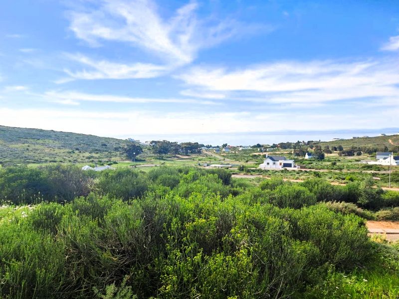 A scenic view overlooking the natural coastal landscape and surrounding residential area, showcasing the open space and terrain of the vacant land.