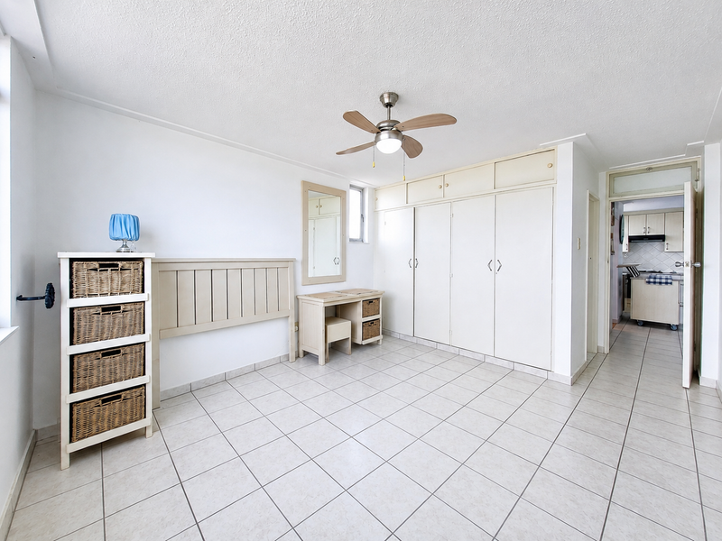 Bedroom featuring tiled flooring, a ceiling fan, and extensive built-in cupboard storage with an integrated vanity area.